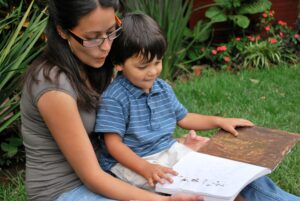 Early Childhood Education. A mother reads to her young, smiling son.